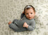 Newborn posing on Hayden Floral fabric featuring sage green and dusty blue wildflowers on a cream background.