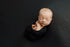 Newborn baby wrapped in a textured, dark charcoal Ocean Ink fabric drop for moody photography.