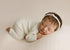 Newborn sleeping on a creamy ivory ribbed knit drop and wrap with subtle peach undertones and delicate texture.