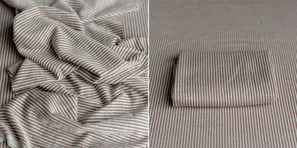 Soft mocha and cream pinstripe stretch fabric for newborn photography, shown folded and draped with a natural texture.