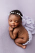 Newborn baby sleeping on a soft, wisteria-purple knit posing fabric and coordinating textured wrap.