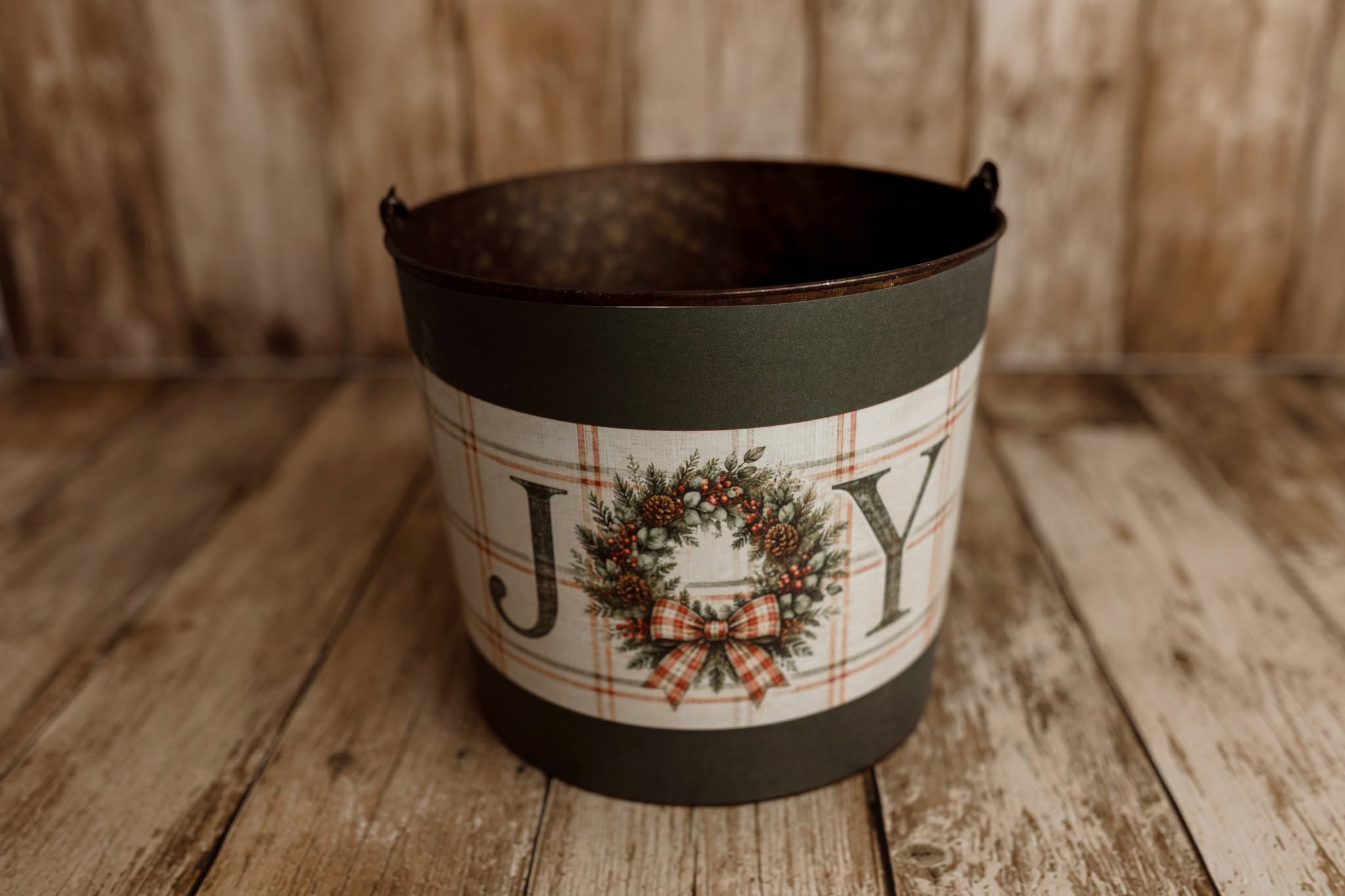 Product photo: Rustic metal newborn posing bucket with Joyful Christmas bucket cover featuring a festive wreath, red plaid bow, and vintage holiday lettering.