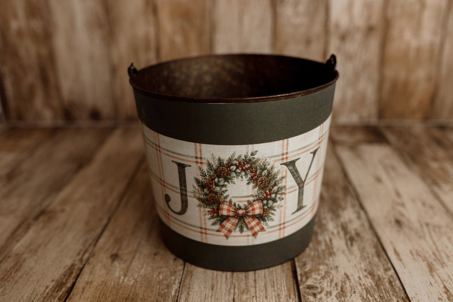 Product photo: Rustic metal newborn posing bucket with Joyful Christmas bucket cover featuring a festive wreath, red plaid bow, and vintage holiday lettering.