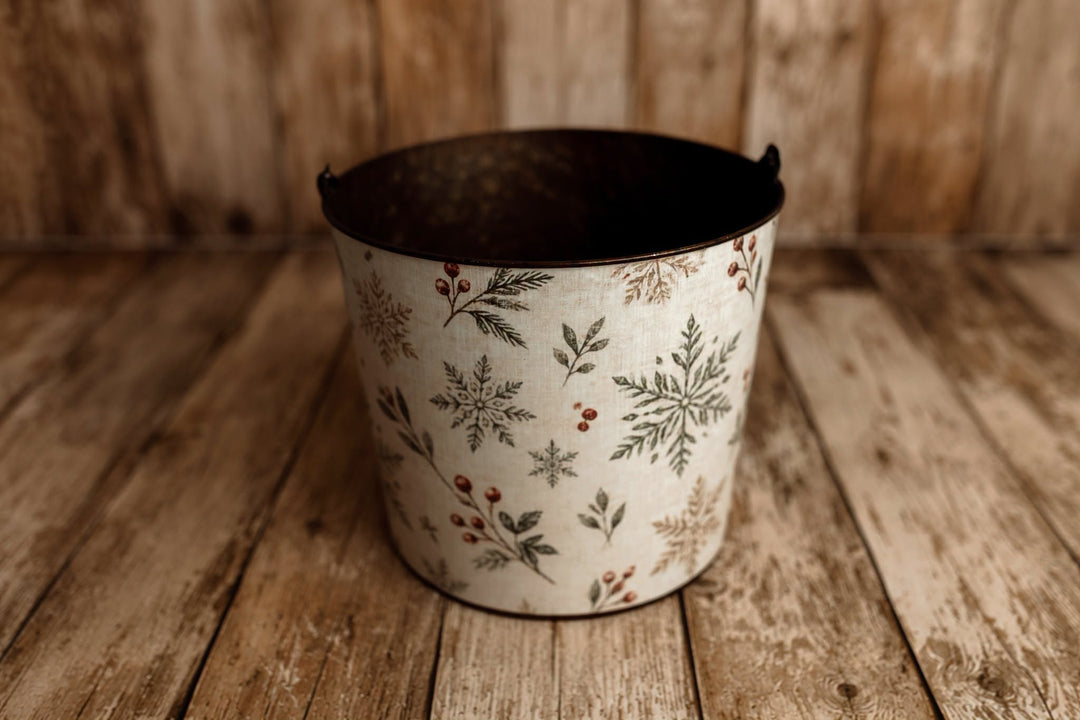 Winter Berry Christmas newborn photography bucket cover featuring green botanical snowflakes, evergreen sprigs, and red berries on cream linen texture.
