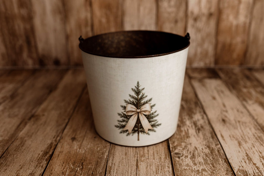 Product photo: Rustic metal posing bucket decorated with Dressed For Christmas removable bucket cover featuring an evergreen tree and neutral bow.