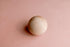 Smooth wooden ball resting on a soft, blush pink textured knit newborn photography backdrop.