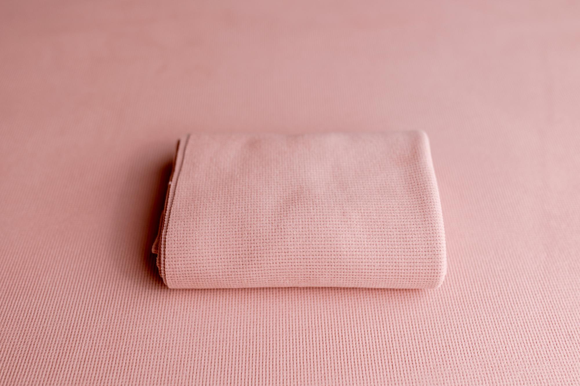 Blush pink newborn photography drop and matching wrap featuring a soft, lightly textured knit fabric.