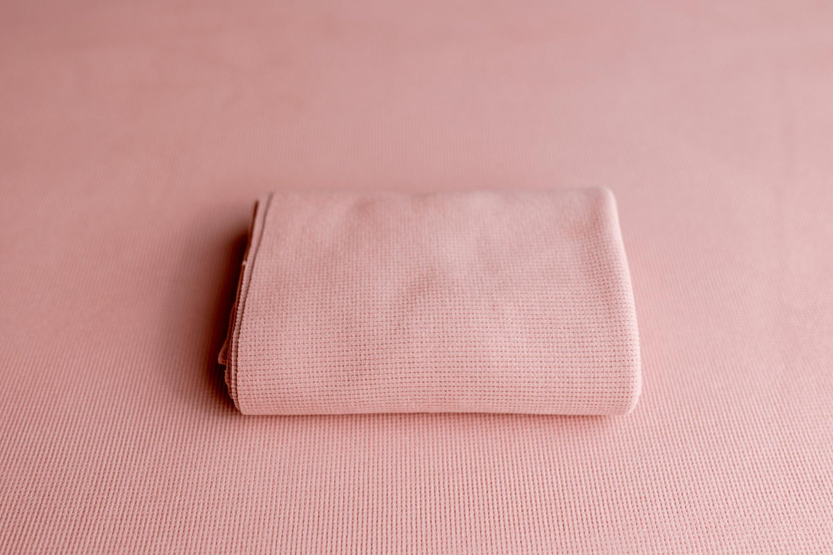 Blush pink newborn photography drop and matching wrap featuring a soft, lightly textured knit fabric.