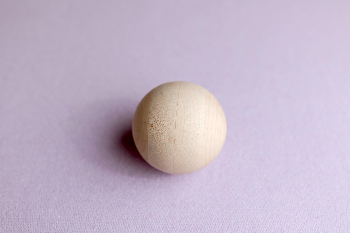 Soft wisteria purple knit posing fabric backdrop with a smooth, light-toned wooden sphere prop.