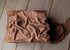 Soft brown-toned purple newborn photography wrap in a lightweight, textured stretch knit fabric draped over a wooden crate.