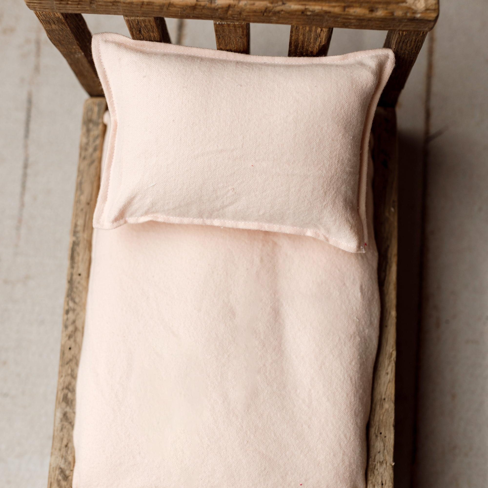 Soft peachy pink linen sheets and pillowcase set for a miniature newborn photography bed prop.