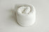A rolled-up white textured knit fabric wrap for newborn photography props.