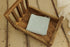 Soft, stretchy light blue fabric folded inside a rustic wooden newborn photography bed prop.