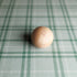 Smooth wooden sphere resting on sage green and cream plaid fabric for newborn photography.