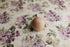 Witney floral posing fabric with watercolor mauve and purple flowers on a creamy neutral base, featuring a wooden sphere.