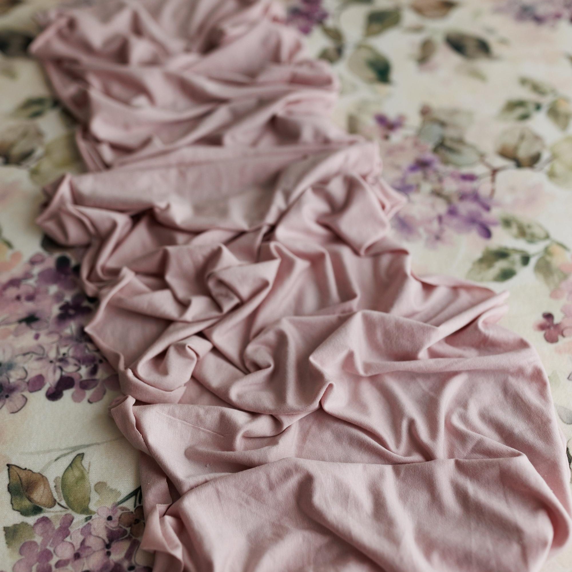 Mauve jersey fabric draped over a creamy floral watercolor posing backdrop.