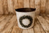 December Morning Christmas newborn photography bucket cover featuring a rustic evergreen and eucalyptus wreath on a softly distressed cream background, displayed on a vintage metal posing bucket against a wooden farmhouse backdrop.