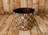 Christmas Scraps newborn photography bucket cover featuring vintage Christmas patchwork squares with evergreen trees, wreaths, rustic plaid, ticking stripes, and botanical details in muted reds, greens, and warm creams, displayed on a metal posing bucket.
