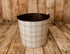 Grandpa's Chair | Original newborn photography bucket cover featuring the bestselling classic beige and cream plaid design with warm neutral tones, displayed on a rustic metal posing bucket against a wooden farmhouse backdrop.