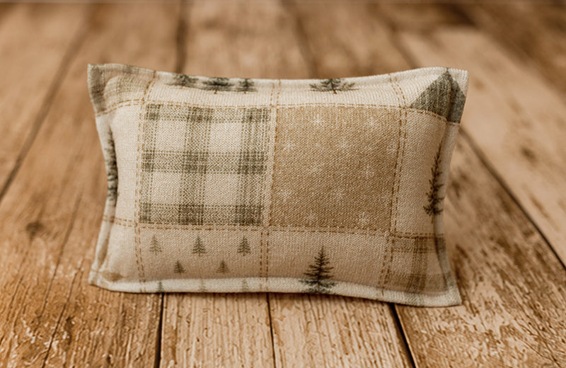 Home For the Holidays newborn photography pillowcase featuring vintage Christmas patchwork with evergreen trees, rustic plaid, and quilt blocks in warm cream, sage green, and muted rust tones, displayed on a wooden farmhouse backdrop.