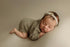 Newborn wearing a taupe open-knit romper with delicate texture, styled for a photography session.