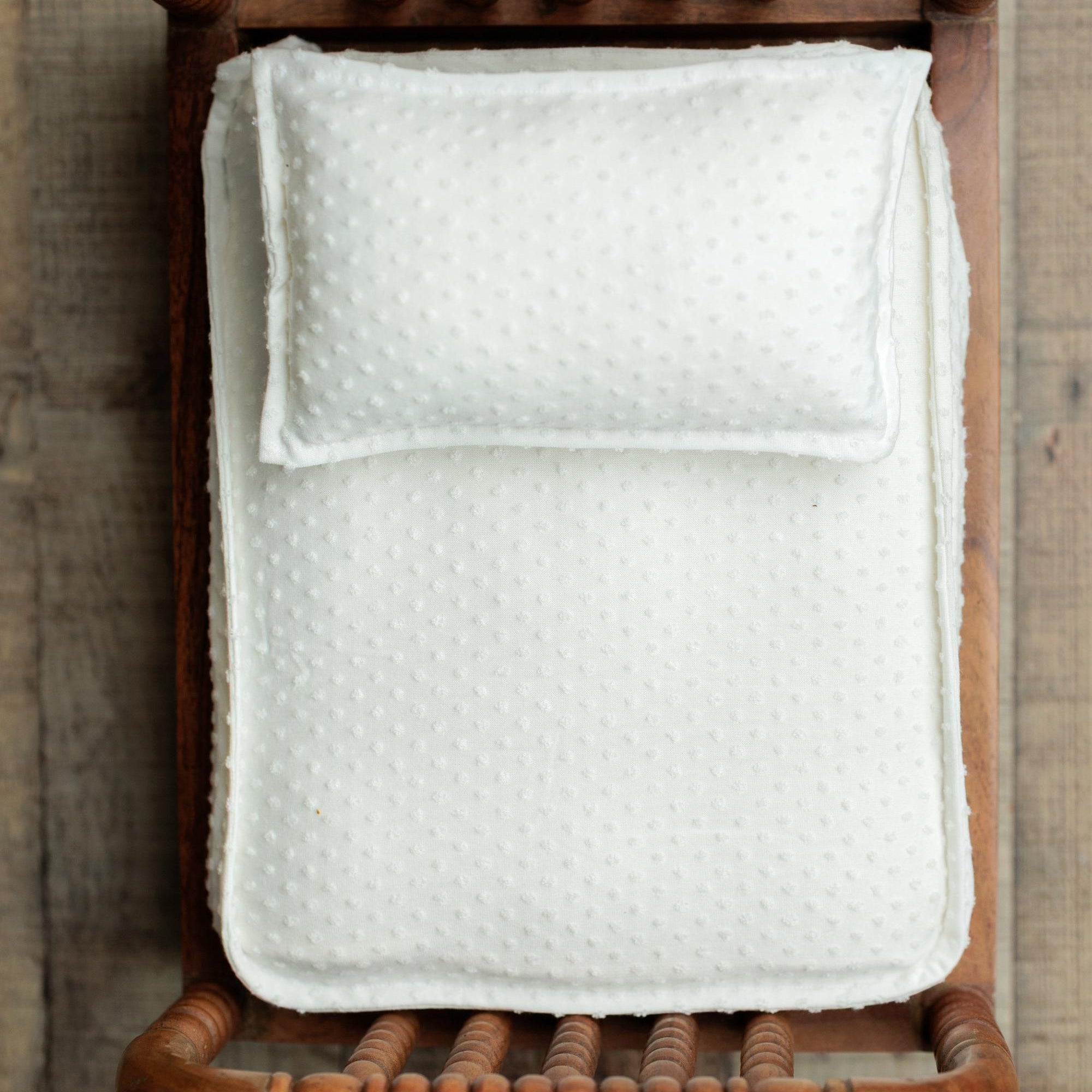 Ivory dobby cotton bedding set with a dotted texture, featuring a coordinating pillow and sheet in a wooden prop bed.