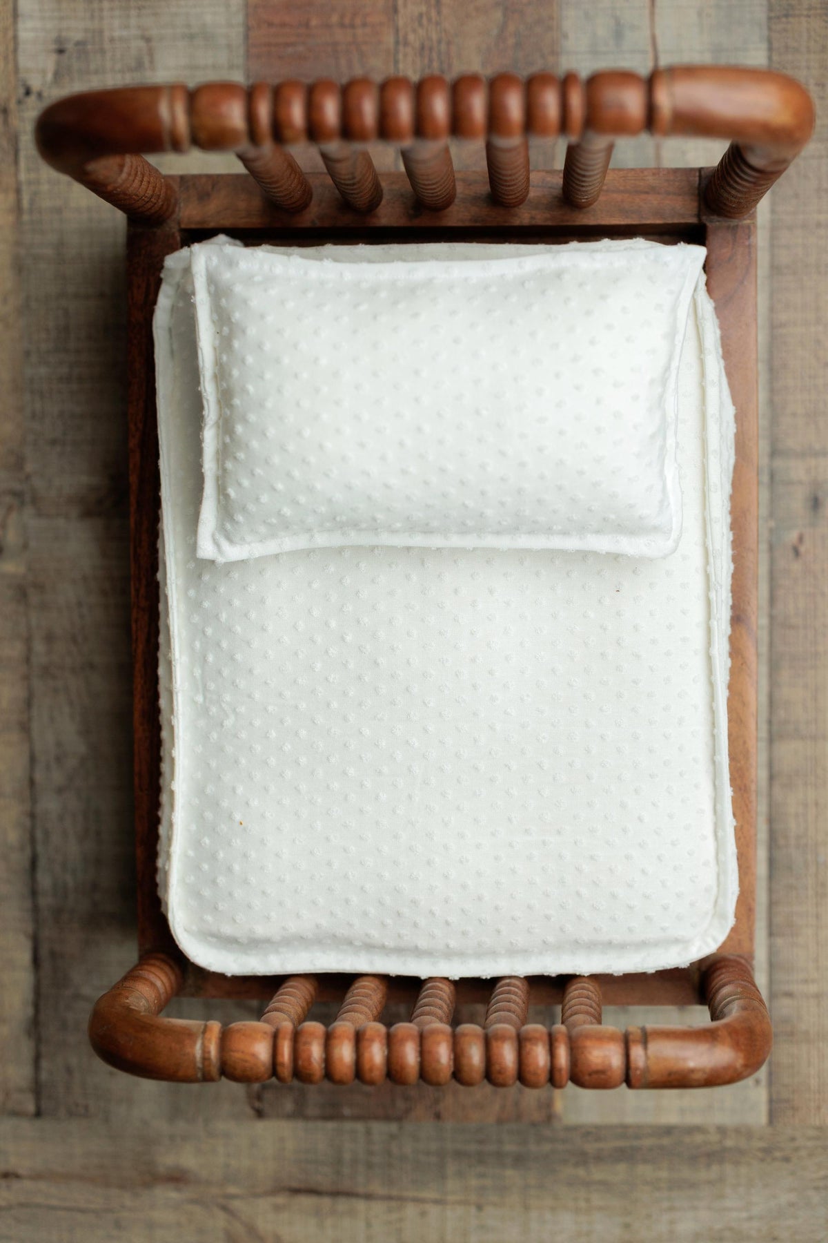 Ivory dobby cotton bedding set with a dotted texture, featuring a coordinating pillow and sheet in a wooden prop bed.