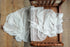 Ivory textured wrap with delicate floral pattern draped over a vintage wooden newborn photography bed.