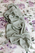 Sage green waffle-knit fabric draped over a creamy floral posing drop with watercolor mauve and purple flowers.