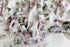 Watercolor floral posing fabric in muted mauve and green on a creamy neutral base with a soft, ruffled edge.