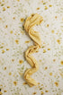 Butter yellow textured knit newborn wrap on an ivory floral fabric backdrop with delicate golden blooms and greenery.