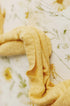 Butter yellow textured knit wrap draped over an ivory floral photography backdrop with golden blooms and greenery.