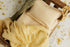 Butter yellow gingham newborn photography bed sheet and matching pillowcase set on a wooden prop bed.