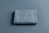 Folded deep dusty blue cashmere-style wrap with a soft, matte texture on a matching fabric background.