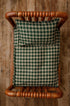 Newborn photography bed set featuring a forest green and cream plaid sheet and matching pillowcase on a wooden bed.