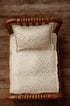 Ivory newborn photography mattress sheet and pillowcase set featuring a metallic gold star pattern on a wooden bed.