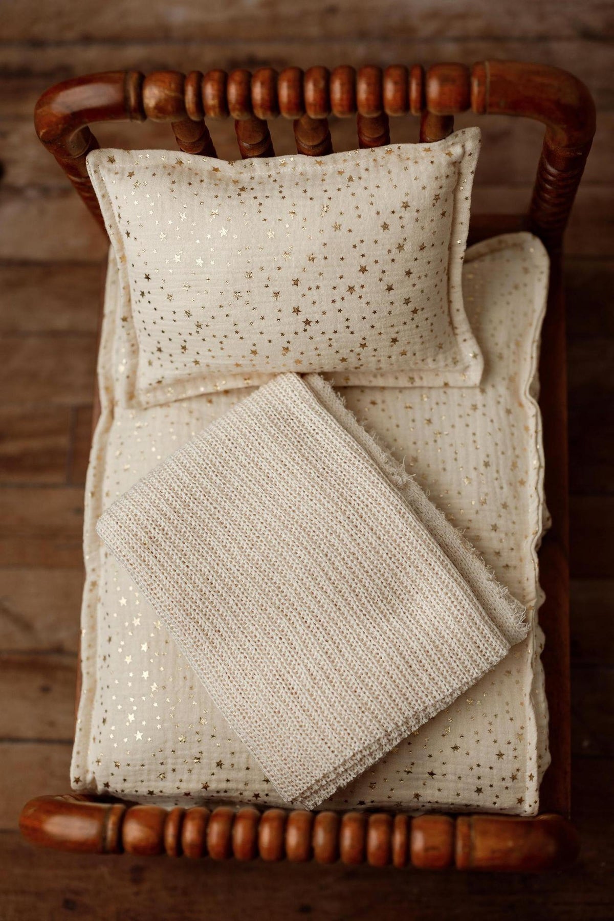 Ivory newborn photography bedding set with metallic gold stars, including a pillowcase, mattress sheet, and textured blanket.