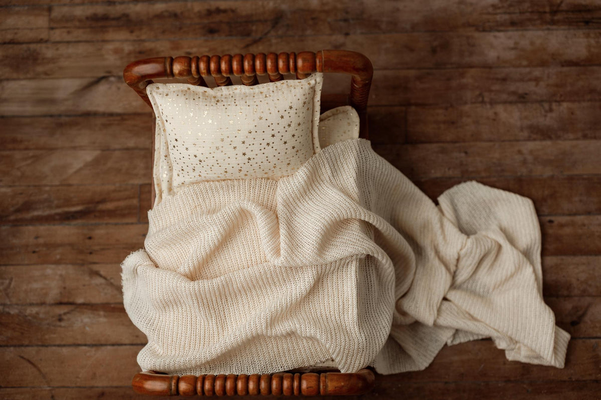 Ivory newborn photography mattress sheet and pillowcase featuring metallic gold stars on a wooden bed frame.