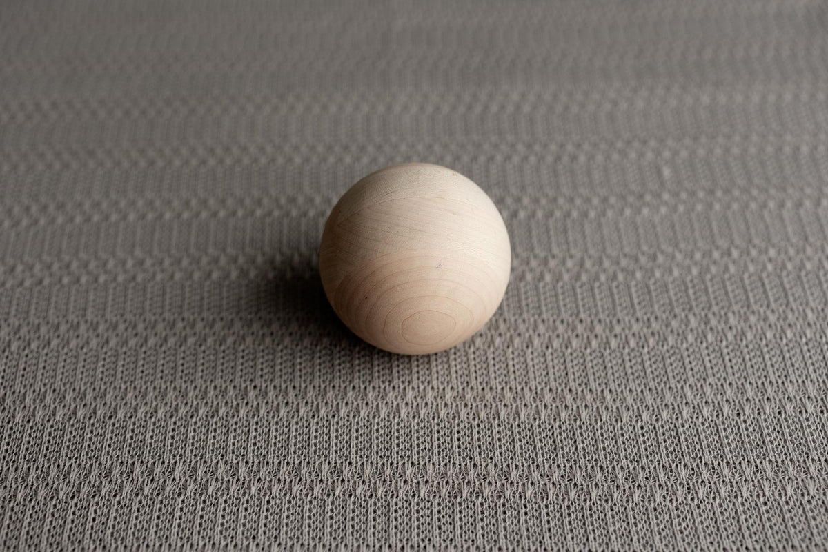 Storm gray textured knit newborn fabric featuring a soft, lightweight weave with a smooth wooden sphere on top.