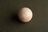 Smooth wooden sphere resting on a deep forest green textured fabric backdrop for newborn photography.