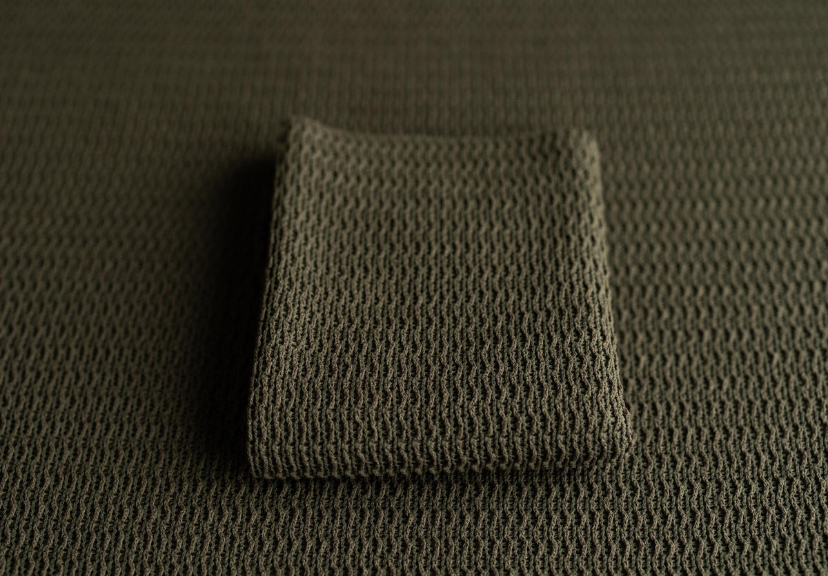 Deep forest green newborn photography fabric with a soft, woven texture and a folded matching wrap.