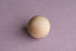 Smooth wooden sphere resting on a textured, muted lavender Nest fabric backdrop for newborn photography.