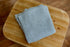Smurf blue newborn photography wrap with a soft, open-knit texture and frayed edges, folded on a wooden surface.