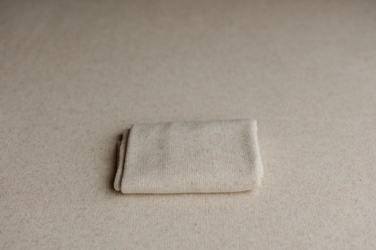 Neutral beige knit newborn posing fabric and matching wrap with soft, textured material for photography backdrops.