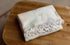 Folded newborn posing fabric with a soft butterfly print and white ruffled trim on a wooden surface.