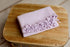 Lavender lilac newborn photography wrap in soft waffle knit fabric with delicate ruffled edging on a wooden surface.
