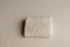 Beige ramen-toned newborn photography fabric wrap with a soft, open-knit texture folded on a matching posing base.