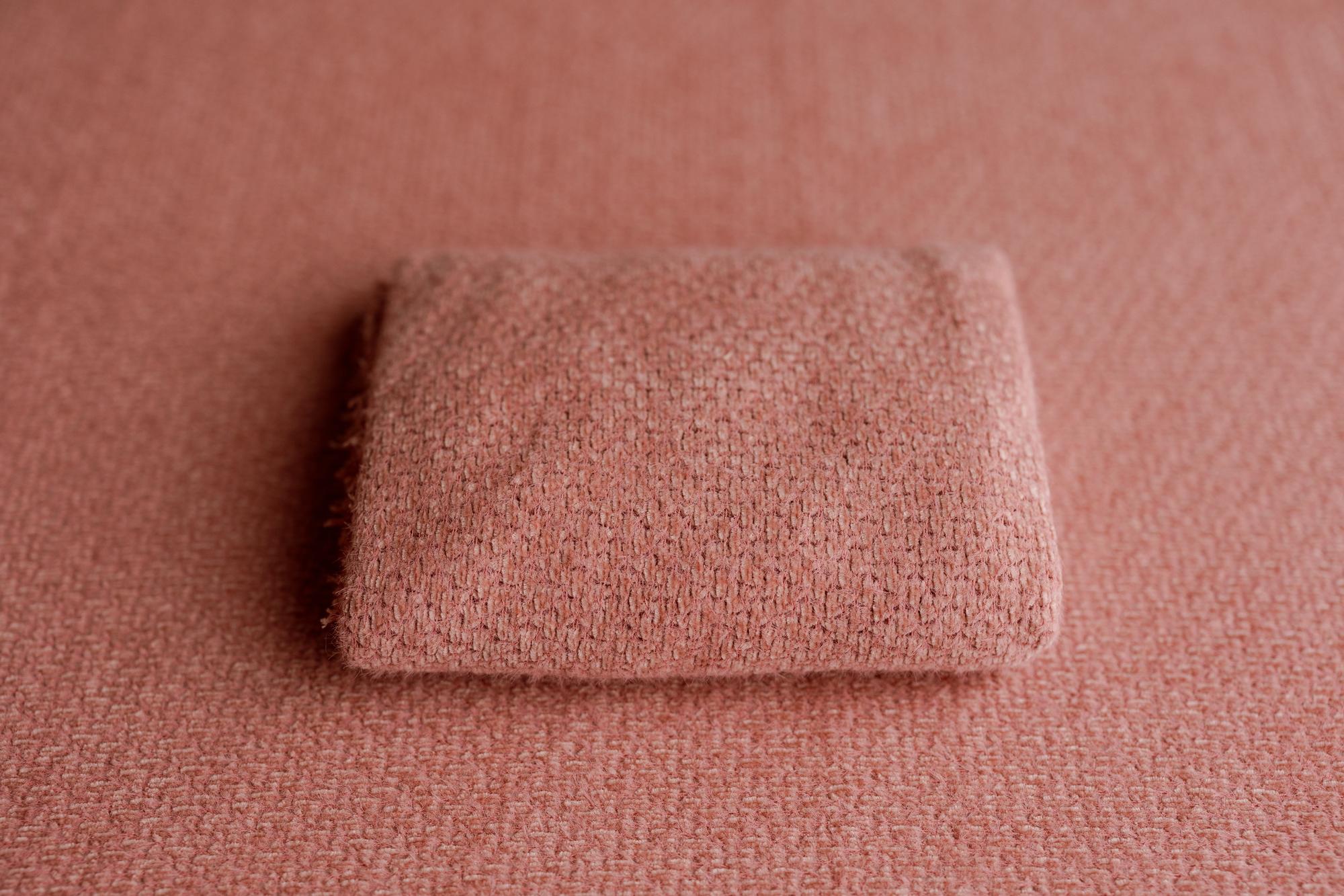 Folded rose-colored Shitshow fabric with a textured, stretchy knit surface for photography backdrops.