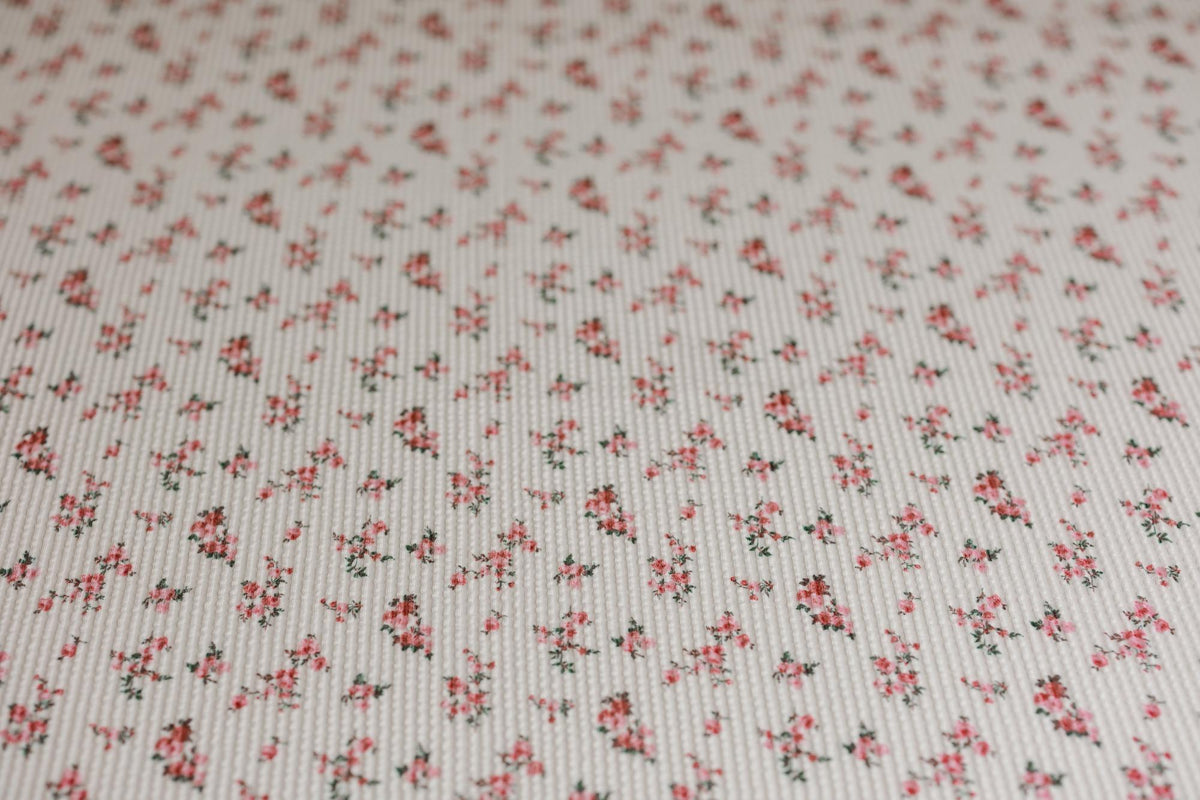 Textured white newborn posing fabric featuring a dainty pink and green floral pattern for photography backdrops.
