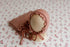Primrose pink floral newborn backdrop with a matching textured ruffle wrap and bonnet on a display stand.